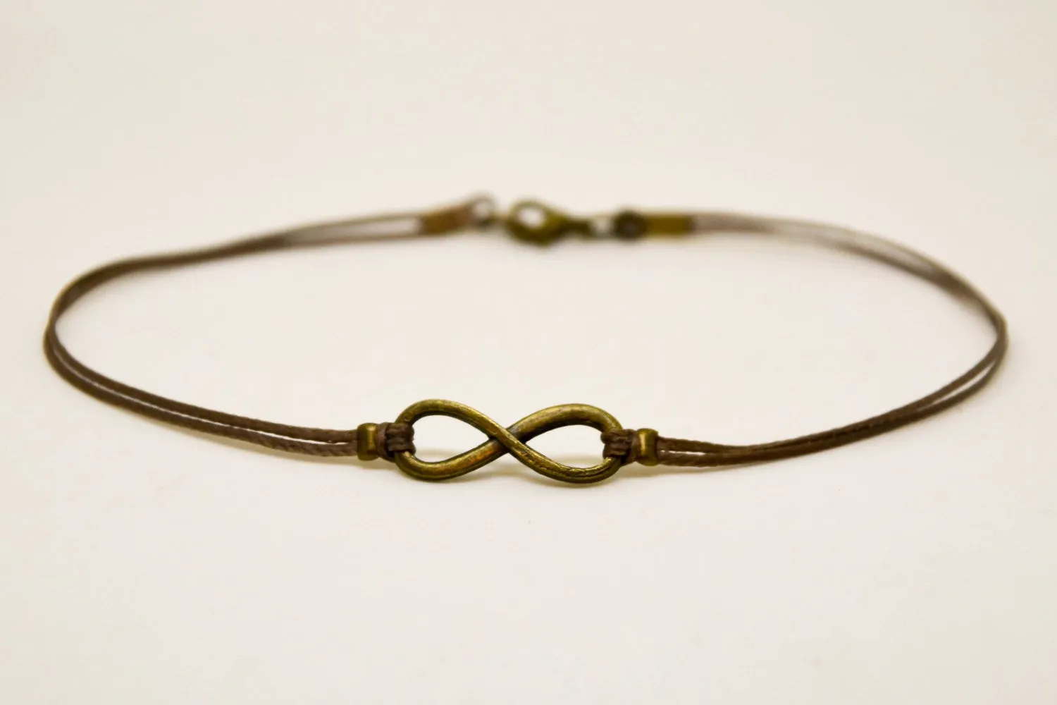 Men's anklet with a bronze tone infinity charm and a brown cord