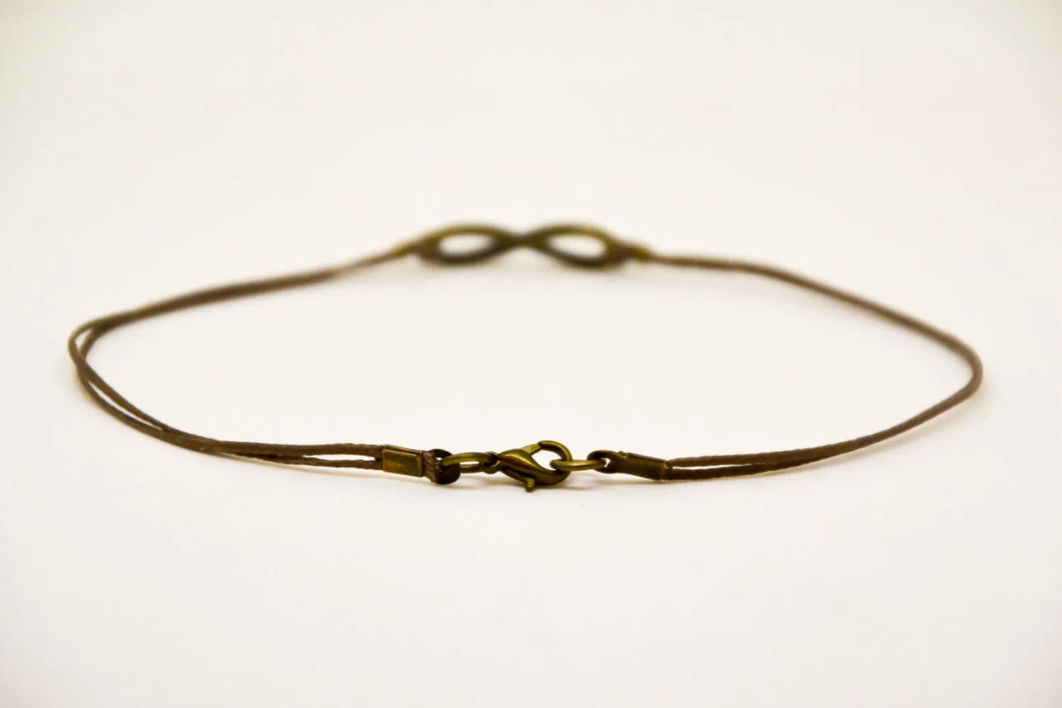 Men's anklet with a bronze tone infinity charm and a brown cord